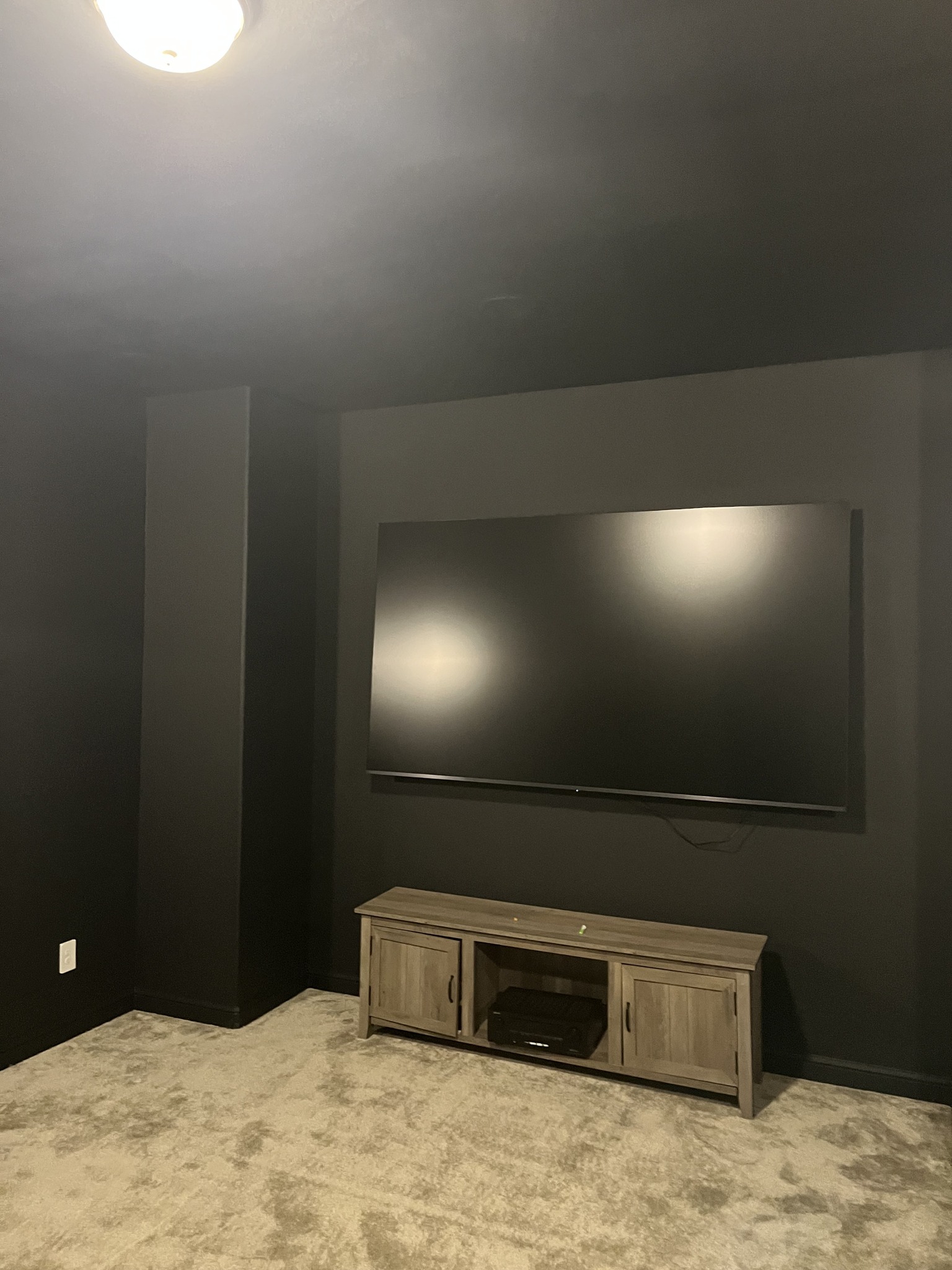 Dark accent wall painting project with clean lines around a mounted television